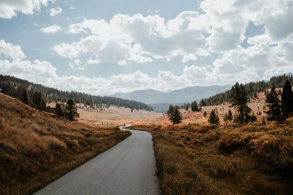 A long winding road in front of a mountain.