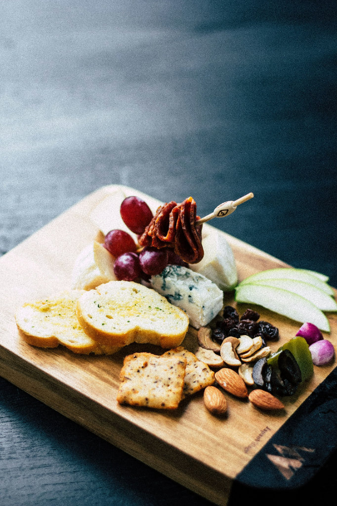 A cheese board with grapes, crackers, toast and nuts